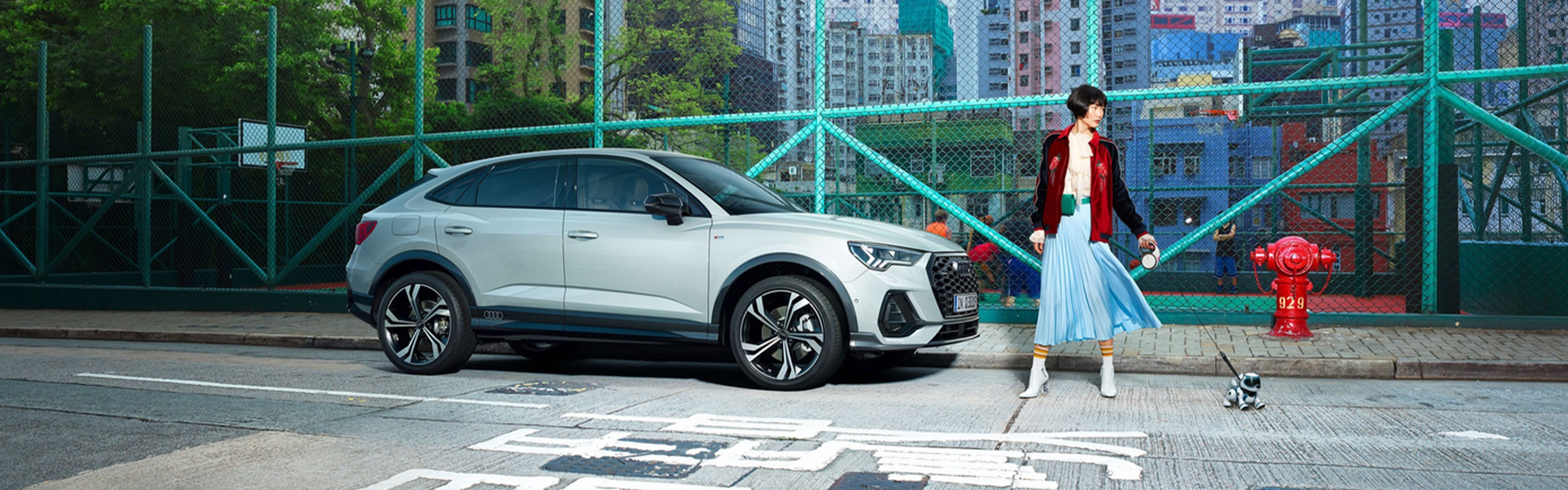 grauer Audi Q3 Sportback TFSI e vor Basketballplatz mit Frau 