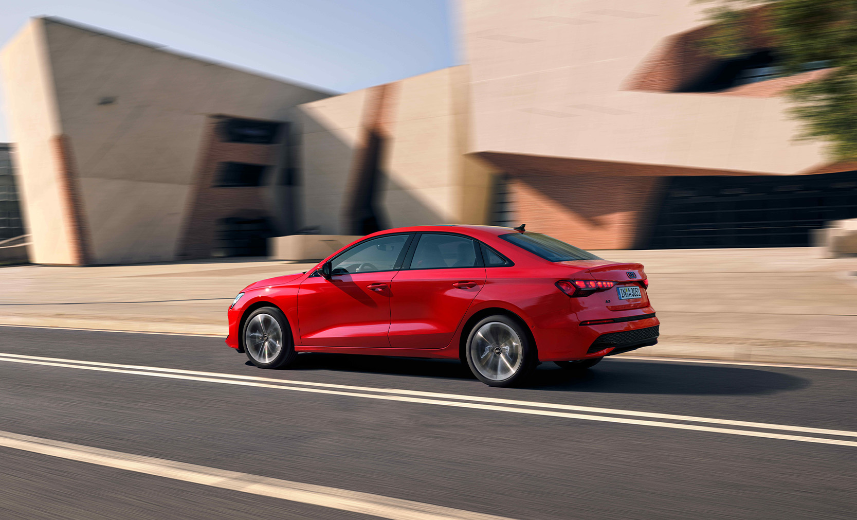 Ein roter Audi A3 fahrend in der Seitenansicht