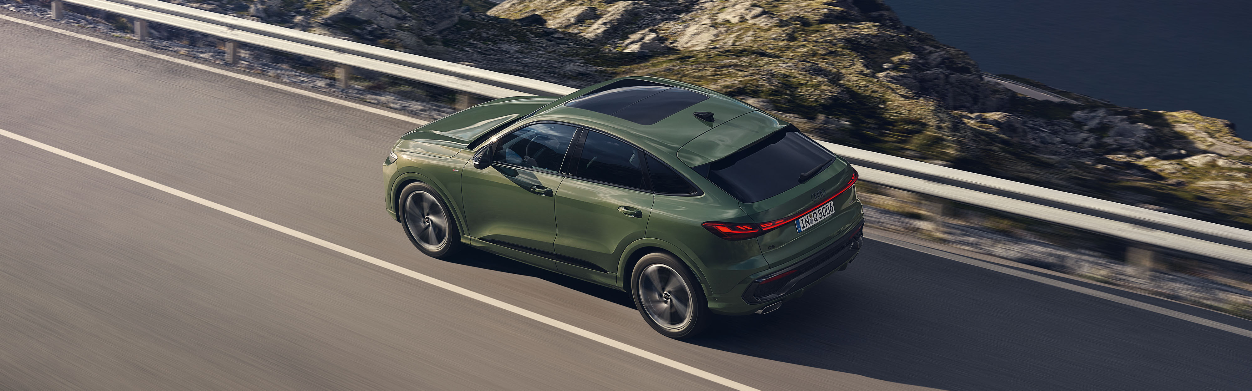 Der neue Audi Q5 Sportback in Gr&uuml;n, in der Dreiviertel-Draufsicht fahrend auf einer Stra&szlig;e