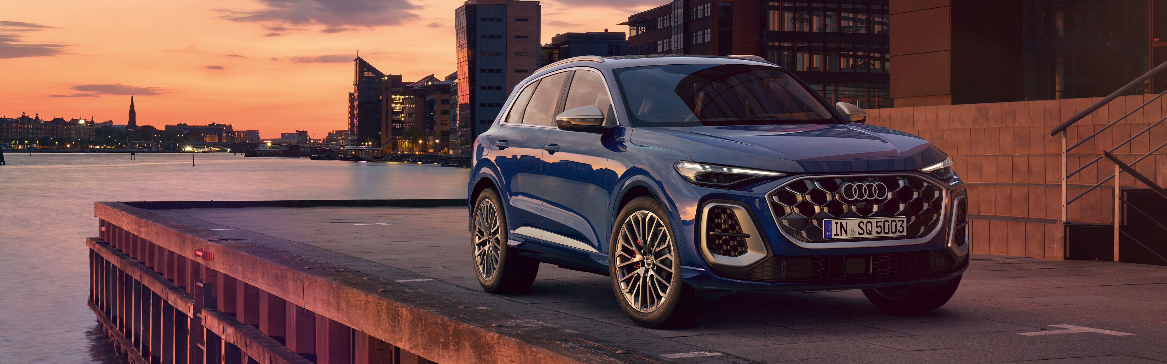 Der Audi SQ5 SUV TFSI in der Dreiviertel Ansicht an einem Hafengel&auml;nder bei Sonnenuntergang