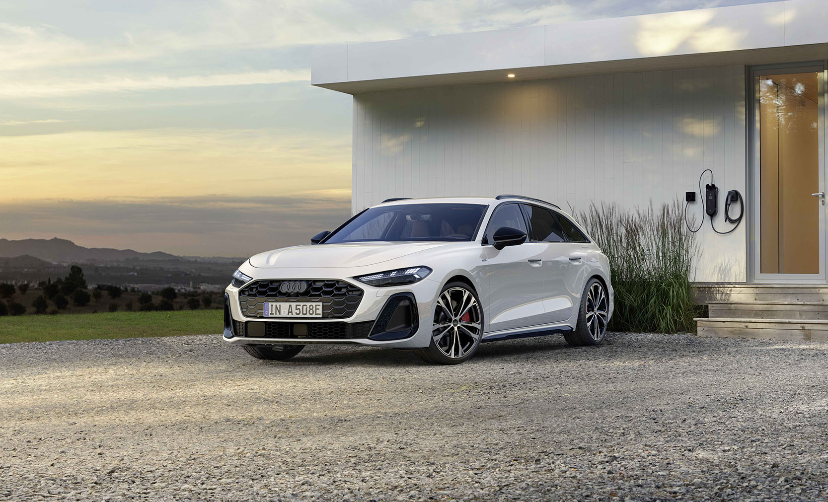 ein wei&szlig;er Audi A5 Avant e-hybrid, Frontansicht vor einem Luxuri&ouml;sen Geb&auml;ude
