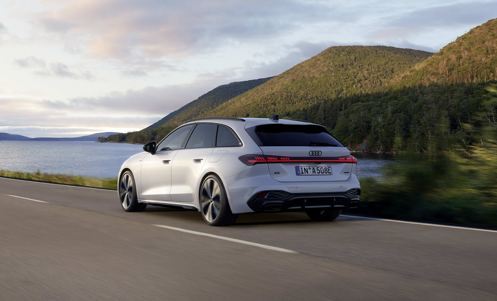 ein wei&szlig;er Audi A5 Avant e-hybrid, Heckansicht w&auml;hrend der Fahrt