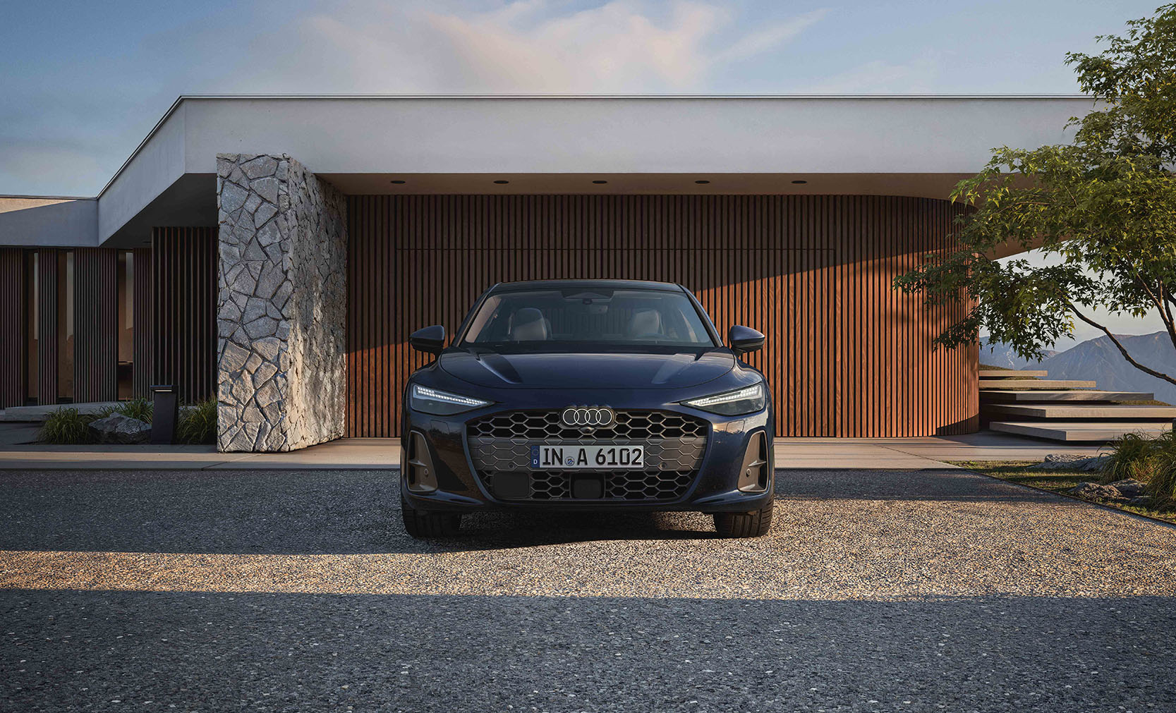 Eine blaue Audi A6 Limousine in der Frontansicht vor einer Luxusvilla