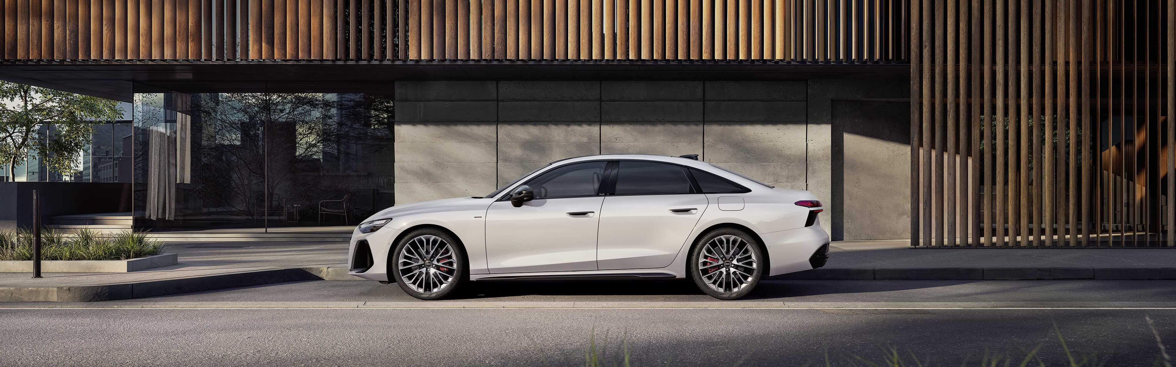 Eine wei&szlig;e Audi A6 Limousine e-Hybrid vor einem futuristischen Geb&auml;ude