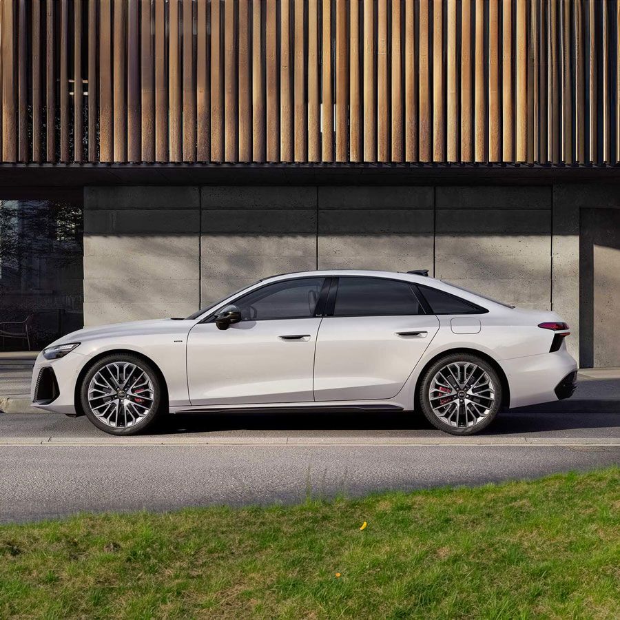 Eine wei&szlig;e Audi A6 Limousine e-Hybrid vor einem futuristischen Geb&auml;ude