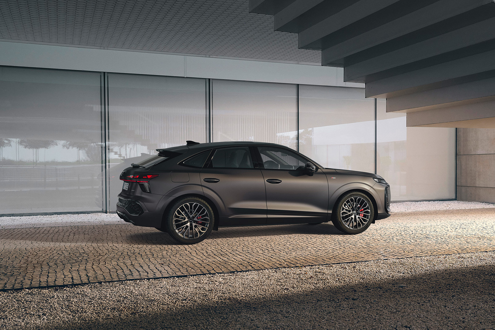 Audi Q3 Sportback, grau, Heck-Seitenansicht vor moderner Hausfassade