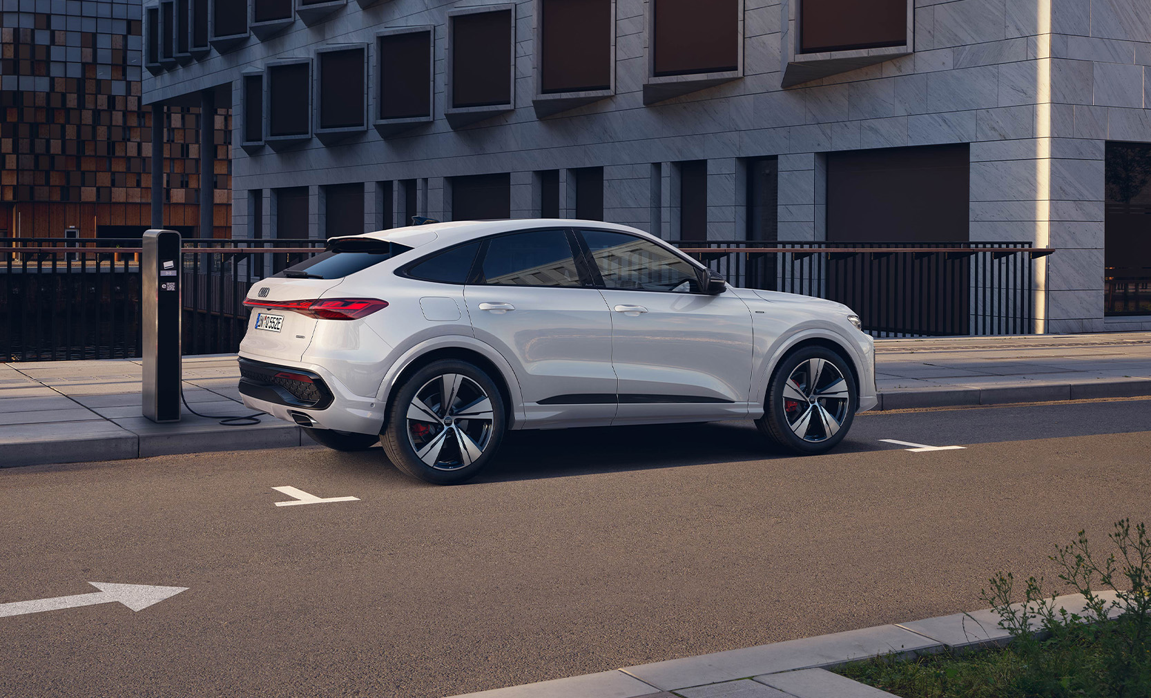 Ein wei&szlig;er Audi Q5 Sportback e-hybrid von seitliche hinten auf der Stra&szlig;e