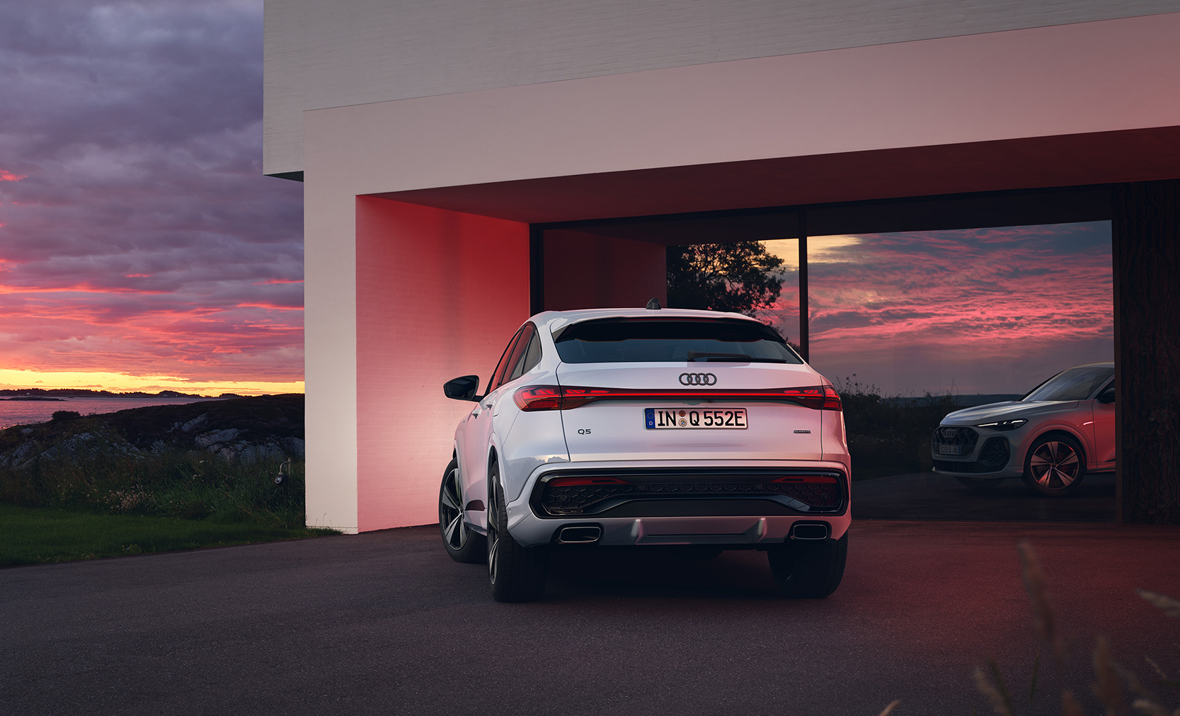 Ein wei&szlig;er Audi Q5 Sportback e-hybrid von hinten vor einer Garage 