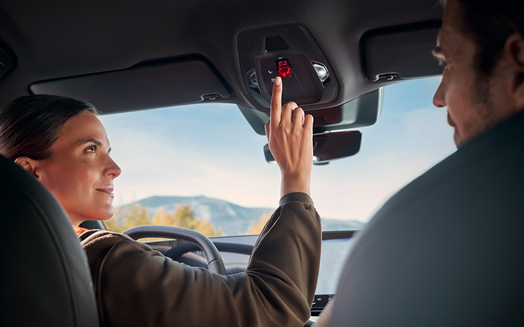 Eine Frau, die in einem Audi sitzt, dr&uuml;ckt die Service-Call-Taste. 