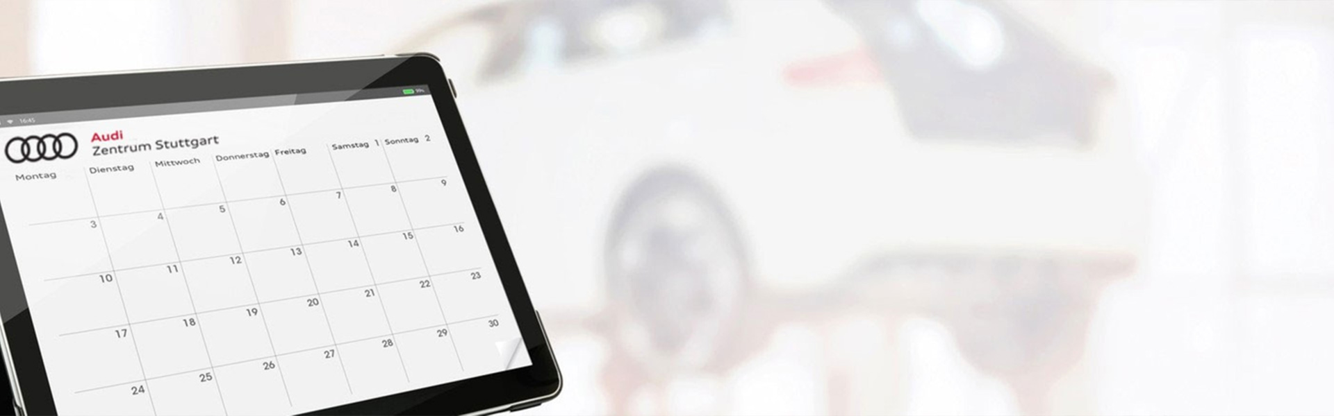 Tablet mit Audi Zentrum Stuttgart Kalender, Fahrzeug auf der Hebeb&uuml;hne im Hintergrund.