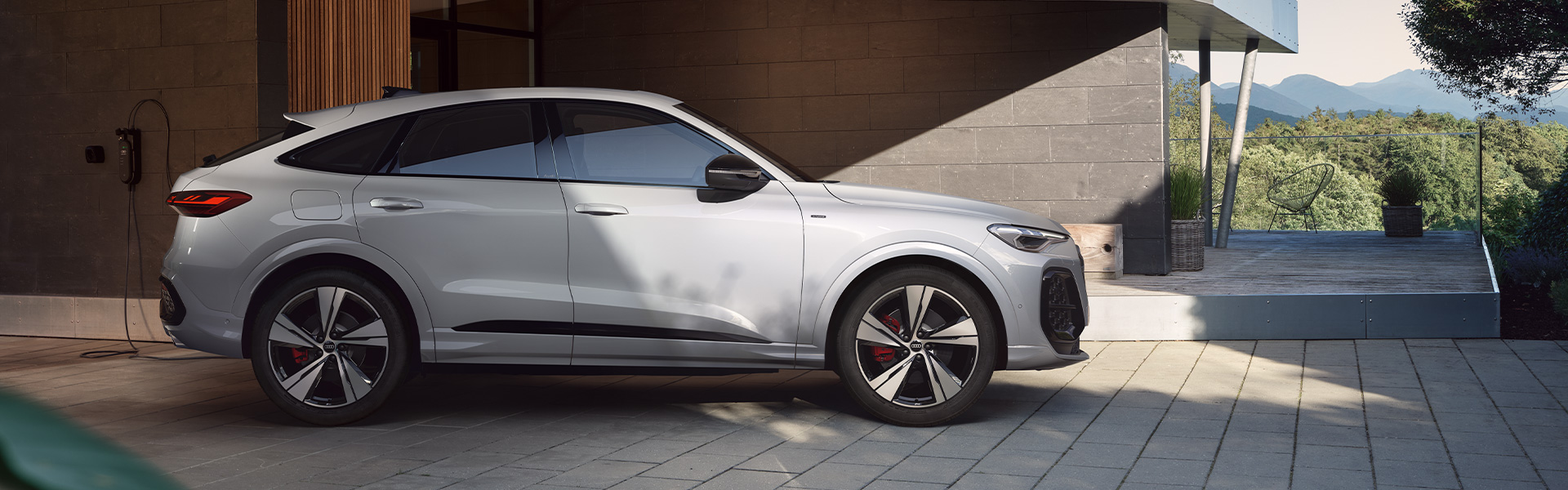 Ein wei&szlig;er Audi SQ5 e-hybrid steht vor einem Geb&auml;ude. 