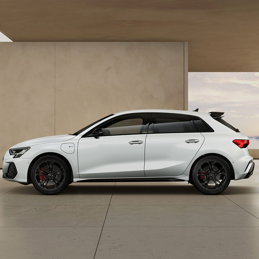 Ein Audi A3 Sportsback TFSI e in Gletscherwei&szlig; Metallic seitlich in beigem Geb&auml;ude