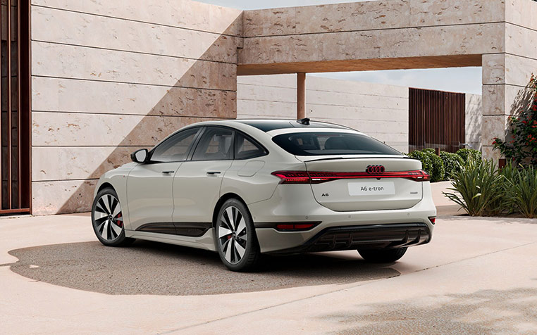 Ein Audi A6 Sportback e-tron seitliche Heckansicht in Siambeige Metallic vor Wohnhaus