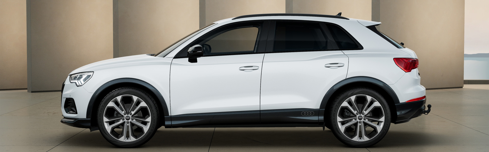 Ein wei&szlig;er Audi Q3 Seitenansicht vor beiger Wand