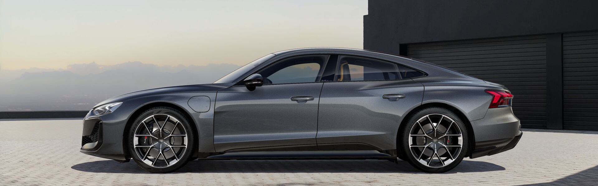Grauer Audi RS e-tron GT seitlich vor schwarzer Garage