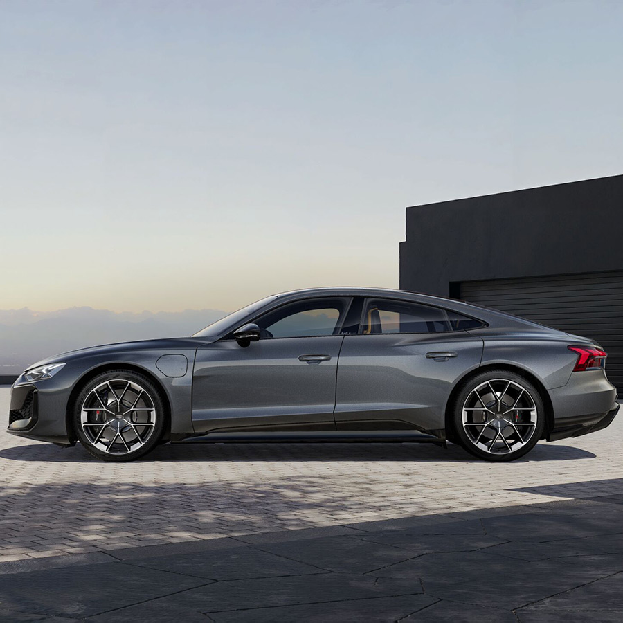 Ein grauer Audi RS e-tron GT vor einer schwarzen Garage mit Bergen im Hintergrund