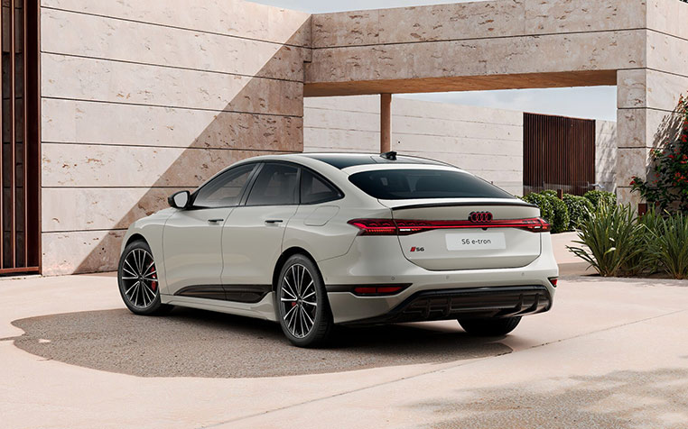 Ein Audi S6 Sportback e-tron in Siambeige Metallic Heckansicht vor Geb&auml;ude