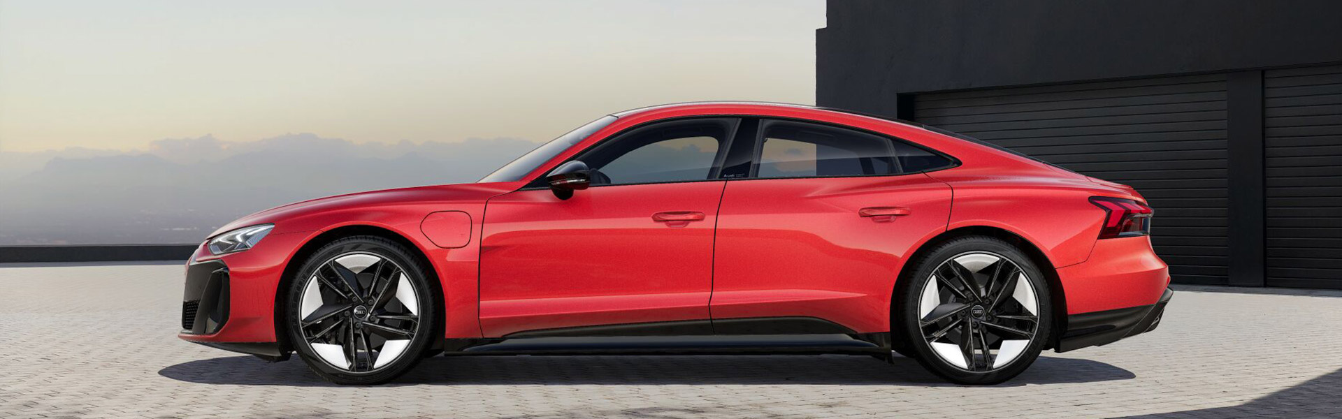 Ein roter Audi e-tron GT quattro seitlich vor einer schwarzen Garage