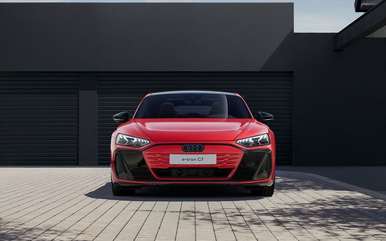 Ein roter Audi e-tron GT quattro Frontansicht vor schwarzer Garage